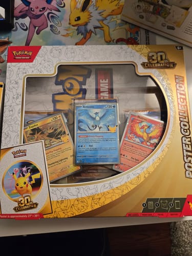 Customer's new Pokemon 30th Celebration Poster Collection box displaying three promo cards through the window