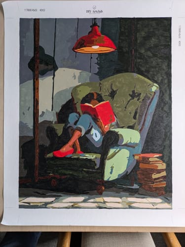Customer's completed Cozy Reading Nook Paint by Number canvas, showing a person reading in a chair under a red lamp