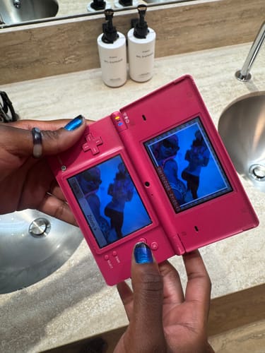 Customer's hands holding a pink electronic gaming device displaying photos of someone wearing Seamless LowRise Leggings
