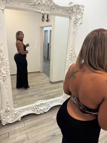 Reviewer in a mirror wearing a black Butter Buckle Wide-Leg Jumpsuit, showing the open back and belt detailing.