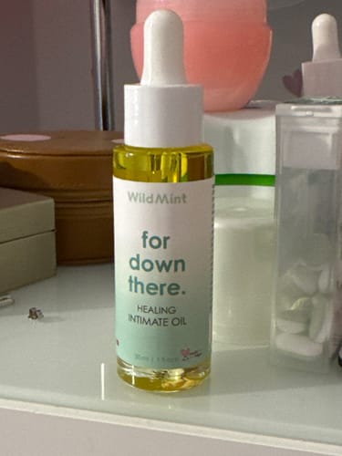 Customer's Healing Intimate Oil bottle on a surface with other skincare products