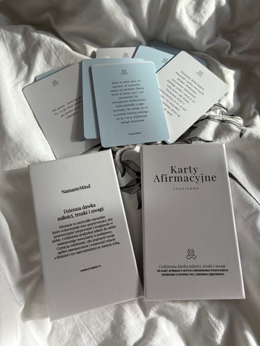 Customer's Karty Afirmacyjne cards spread on white fabric, showing text in Polish.