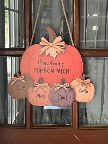 Customer's personalized wooden Grandma and Grandpa's Pumpkin Patch door hanger hanging on a dark wood door.