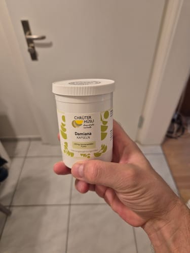 Customer's hand holding a white bottle of Chrüter Hüsli Damiana Kapseln.
