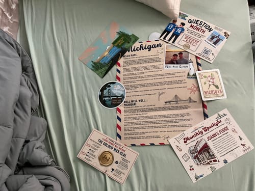 Reviewer's Josh & Jase Mail Club Michigan mailer set including a letter, postcards, stickers, and informational cards.