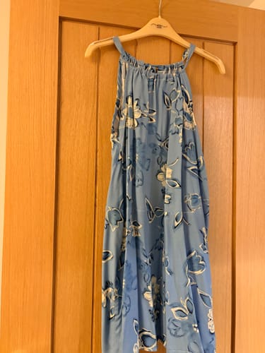 Customer's summer dress made from the blue floral Vintage Posy Viscose Challis fabric hanging on a wooden hanger.