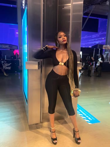 Customer's black Naked Cutout Capri Jumpsuit with gold hardware, worn with heels in a venue.