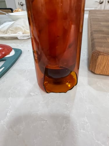 Reviewer's amber FLUR Iced Coffee Glass sitting on a counter with a large, sharp crack at the base.
