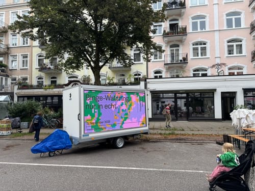 Kundenfoto der blauen Tarpofix Deichselabdeckung, montiert an einem Anhänger vor einem Wohngebäude.