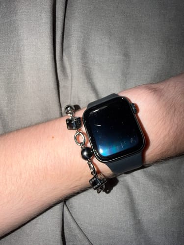 Customer's Lucky Bracelet worn on a wrist alongside a dark smartwatch