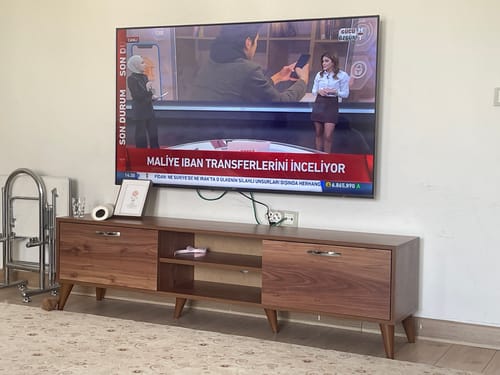 Customer's Rani A9 TV ünitesi, minyatür ceviz renkli ayaklı sehpa, evde televizyonun altında kurulu halde.