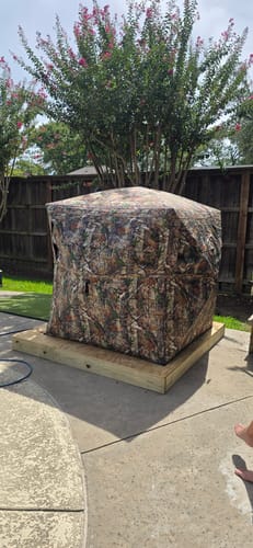 Reviewer's VisX See Through 300D Hunting Blind set up on a wooden platform in a backyard.