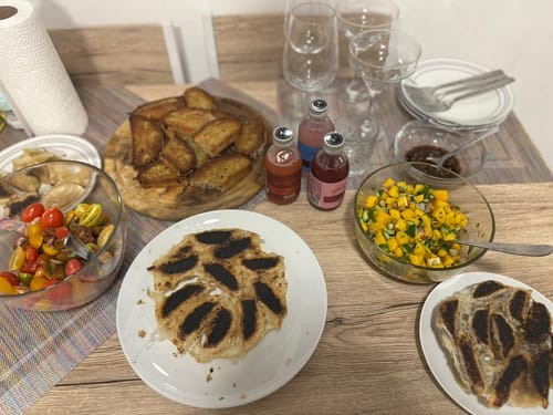 הסנגריה הלבנה של הלקוח מוגשת על שולחן לצד מנות אוכל, כוסות יין וצלחות.