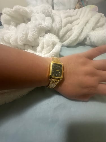 Reviewer's gold Claire De Mains watch with a black face worn on their wrist