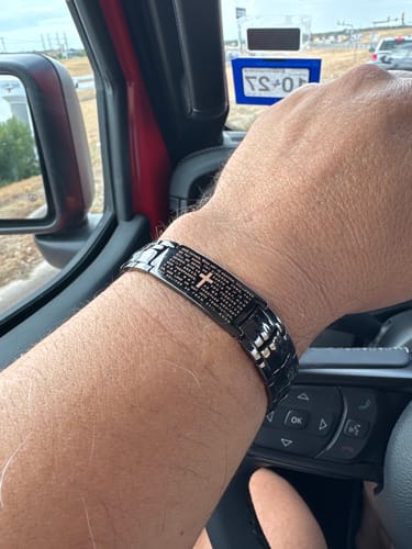 Reviewer's black magnetic Power of the Lord’s Prayer bracelet worn on their wrist while inside a vehicle.