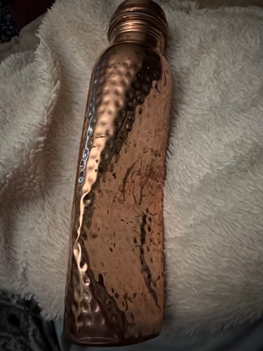 Customer's hand-hammered copper water bottle, showing a significant dent in the side from impact.