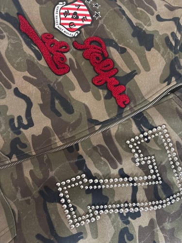 Customer's Aelfric Eden camo zip-up hoodie featuring red embroidered logo patches and a metallic studded number 77.
