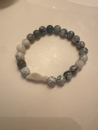Customer's Glide Bracelet featuring a mix of grey and white marbled beads and a small, beige seal-shaped charm.
