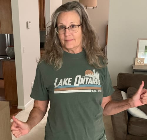 Reviewer wearing a green Lake Ontario retro striped t-shirt with a lighthouse design, giving a thumbs up.
