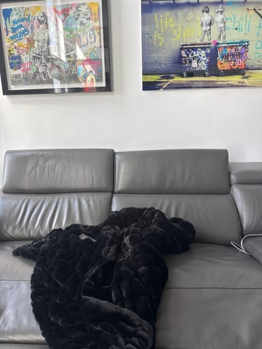 Customer's plush, black Hugs Black Blanket draped over a gray sofa.