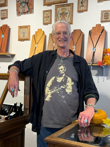 Customer's Lincoln Guitar T-Shirt worn by a person smiling in a shop with jewelry displays.