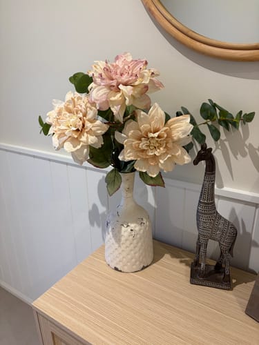 Customer's distressed white Michelle French Provincial Bottle Vase styled with flowers on a wooden table.
