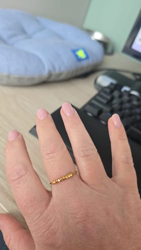 Customer's hand wearing the thin gold Alison Fidget Ring with small, hexagonal beads on their finger.