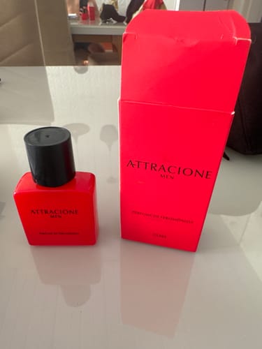 Customer's Attracione Men perfume bottle and its tall, bright red packaging box sitting on a table.