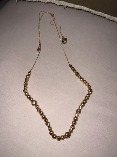 Customer's Collar Cordón Bolitas Machacadas Boho necklace with gold-toned, textured metallic beads on a thin cord.