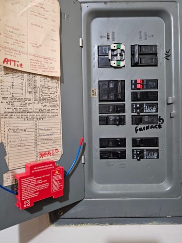 Customer's bright red NovaCare Fire Guard installed inside a grey electrical breaker panel door.