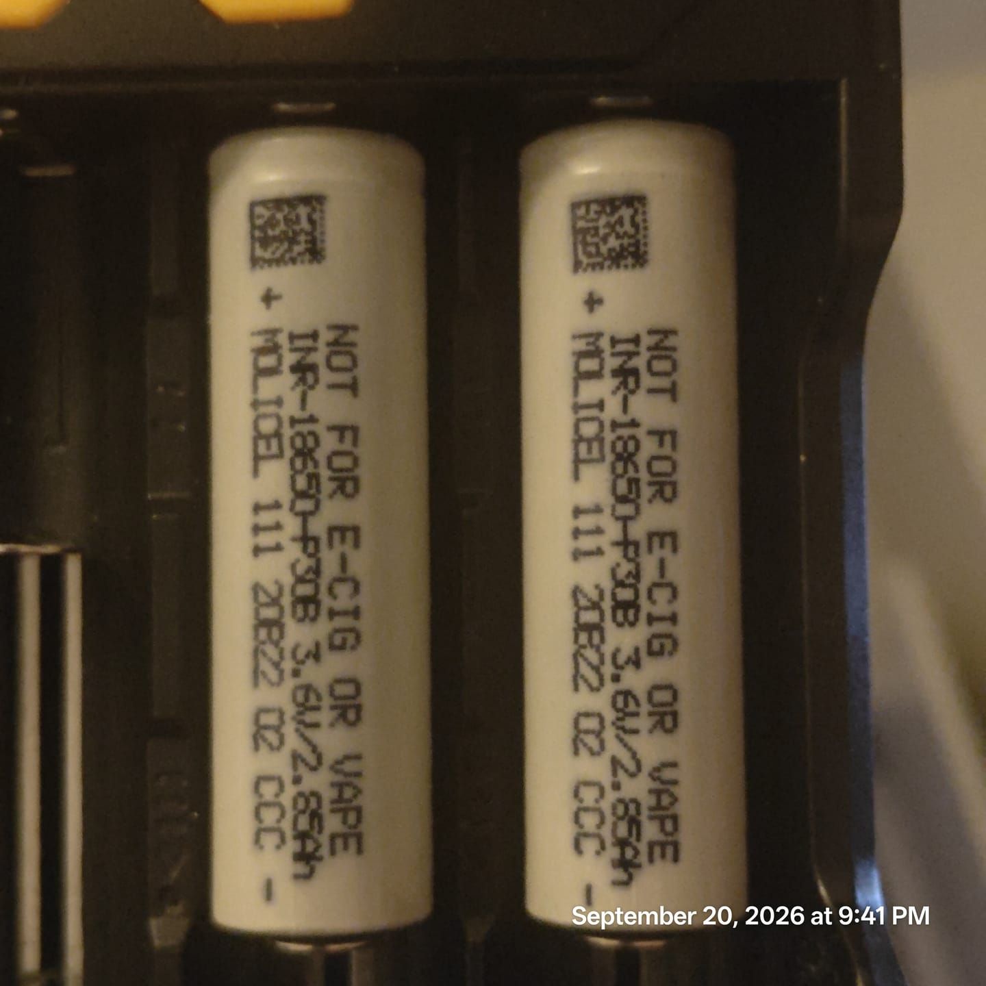 Two white Molicel INR-18650-P30B cells seated side by side in the bays of a black charger