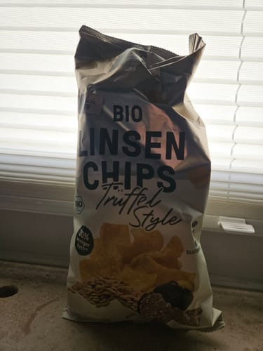 Customer's pack of Bio Linsen Chips Trüffel-Style standing in front of a window.
