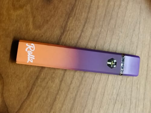 Customer's Rollz 10-OH Vape pen with an orange-to-purple gradient finish, lying on a wood surface.