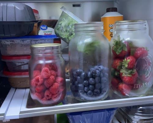 Customer's Mason Genie Vacuum Sealer Kit used on three glass mason jars of berries stored inside a refrigerator.