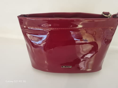 Customer's burgundy Estuche Charol, showing the shiny exterior and Lounge brand logo.