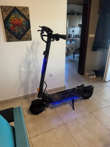 Customer's Ausom DT2 Pro electric scooter parked indoors on a tiled floor near a framed picture