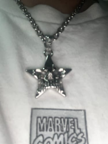 Customer's blurry SKAR pendant on a chain, showing the silver star design and the connecting loop.