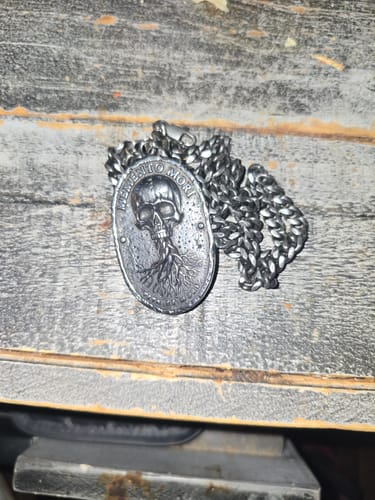Customer's Memento Mori Vita Et Mors necklace with skull medallion and chain resting on a wood surface.