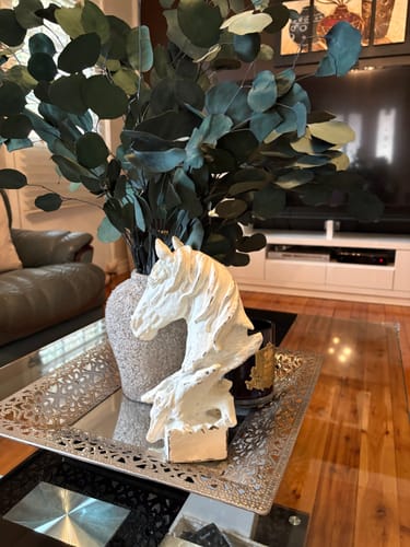 Customer's distressed white Cosimo horse head bust displayed on a mirrored tray with a vase of eucalyptus.