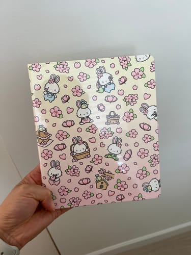 Reviewer's hand holding a Blossom Bunnies A5 Wide Planner with a cute bunny and cherry blossom pattern.