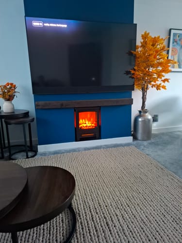 Customer's dark oak fireplace beam installed as a mantel shelf above a fireplace, mounted on a blue wall.