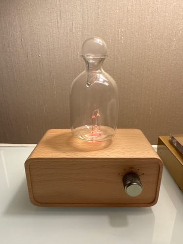 Customer's Aura Nebulizer with a clear glass reservoir atop a smooth light wood base on a desk