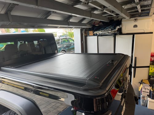 Customer's black aluminum OPENROAD tonneau cover installed on the truck bed in a garage.