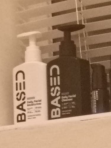 Customer's Daily Skincare Duo containing a white moisturizer bottle and a black facial cleanser bottle on a ledge.