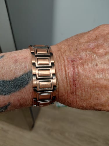 Reviewer's copper magnetic bracelet on wrist, showing the linked design and wide metal segments.