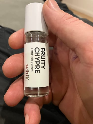 Reviewer holding a small, clear glass roller bottle of Fruity Chypre fragrance with a white cap.