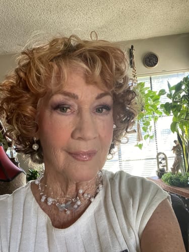 Customer's smiling selfie wearing a pearl necklace, showing off glowing skin after using Deep Collagen Cream.