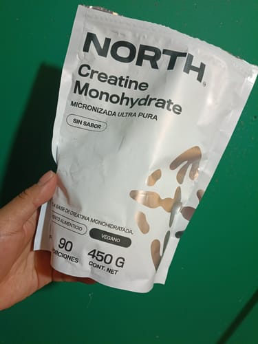 Customer's hand holding a white bag of NORTH Creatine Monohydrate, 450g