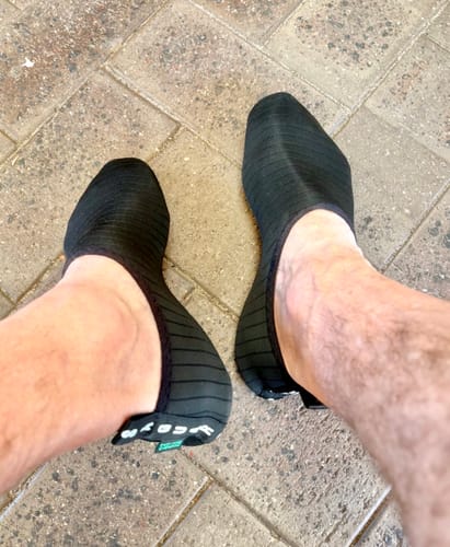 Customer's Touch IV shoes worn on feet, showing the flexible, black microfiber material on a paved surface.