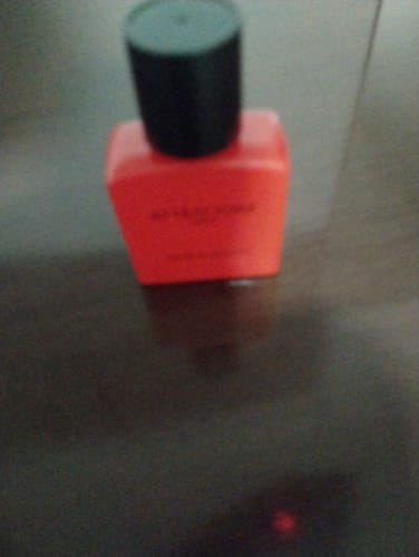 Customer's Attracione Men perfume bottle, red glass with a black cap, slightly blurry.
